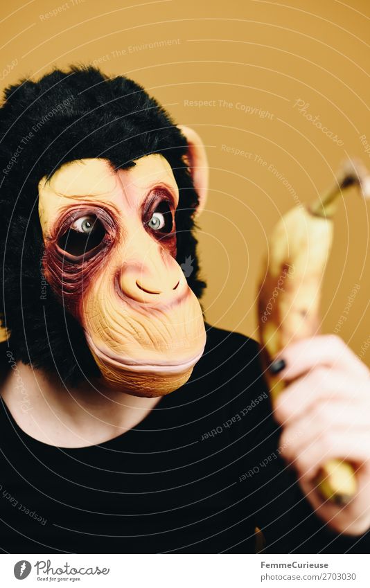 Person with monkey mask starring at banana Freude 1 Mensch Ernährung Lebensmittel Frucht Banane Evolution Essverhalten Affen Schimpansen Karneval