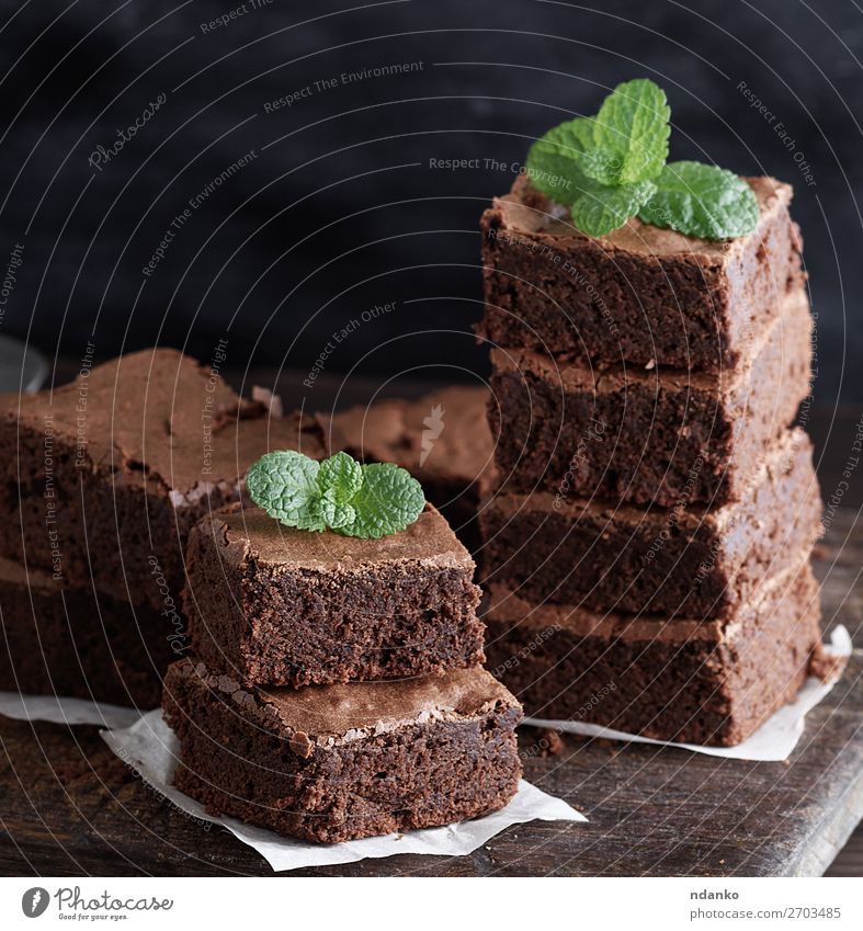 Stapel von quadratischen Stücken von gebackenem braunem Brownie Pie. Kuchen Dessert Süßwaren Ernährung Tisch Blatt Holz dunkel frisch lecker grün schwarz