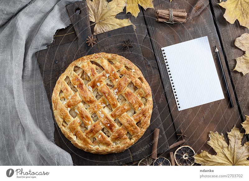 runde Apfelkuchen auf einem braunen Holzbrett Frucht Kuchen Dessert Süßwaren Abendessen Tisch Küche Herbst Blatt Papier Schreibstift oben gelb weiß Tradition