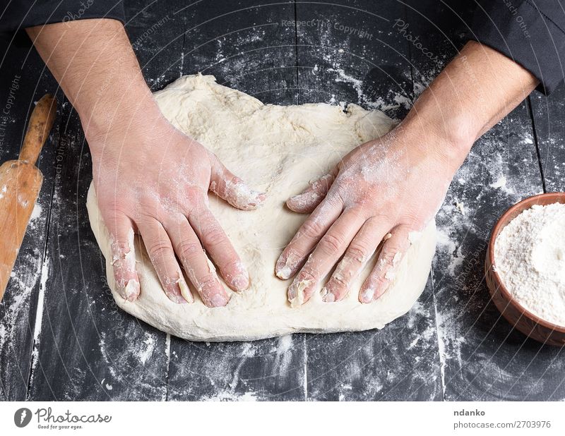 Männerhände kneten ein rundes Stück Teig für die Herstellung von Pizza. Teigwaren Backwaren Brot Ernährung Schalen & Schüsseln Tisch Küche
