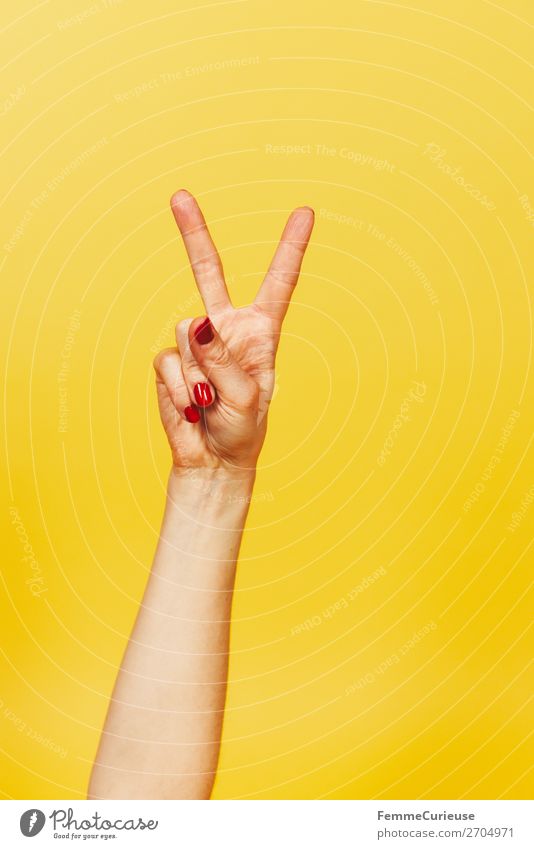 Hand signal for victory against a yellow background feminin Frau Erwachsene 1 Mensch 18-30 Jahre Jugendliche 30-45 Jahre Kommunizieren Erfolg Sieg gestikulieren