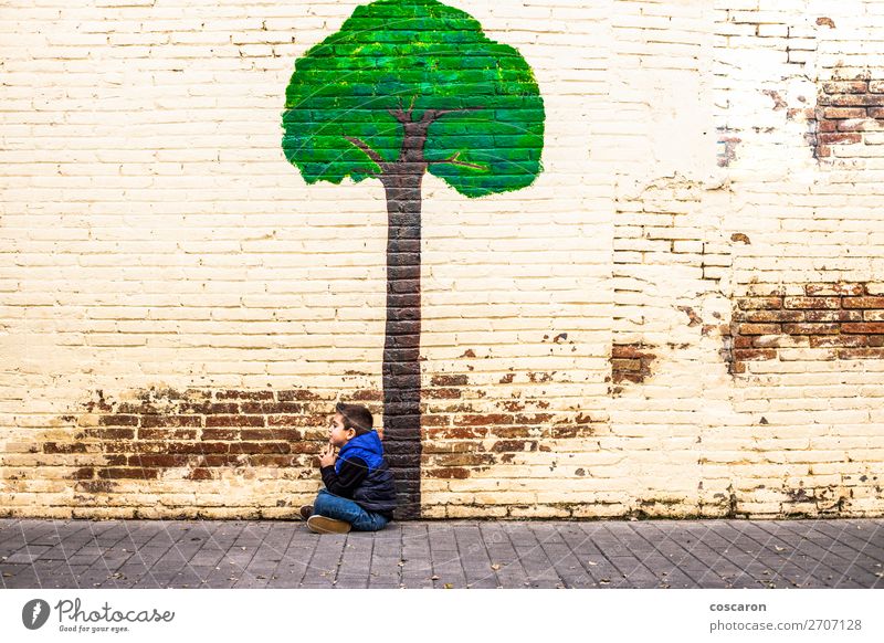 Kleines Kind, das unter einem Baum sitzt, der an einer Wand gemalt ist. Freude Glück schön Spielen Abenteuer Winter Garten Klettern Bergsteigen Mensch Baby