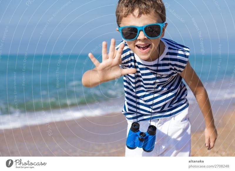 Ein glücklicher kleiner Junge, der tagsüber am Strand spielt. Er ist mit einer Matrosenweste bekleidet. Ein Kind, das sich draußen amüsiert. Konzept eines Matrosen im Urlaub.