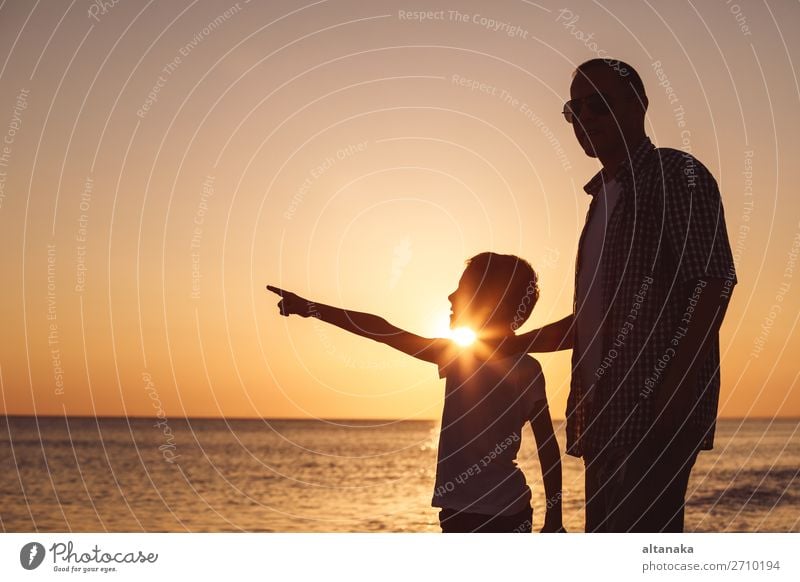 Vater und Sohn spielen zur Zeit des Sonnenuntergangs am Strand. Die Menschen haben Spaß im Freien. Konzept eines glücklichen Urlaubs und einer freundlichen Familie.