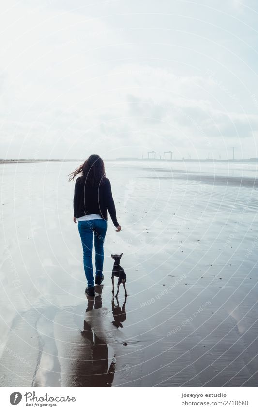 Frau und ihr kleiner Hund am Strand Lifestyle Erholung Winter Erwachsene Freundschaft Natur Landschaft Sand Horizont Brücke Jeanshose brünett Liebe blau 1812