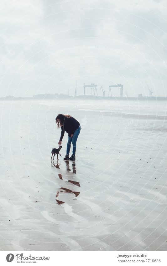 Frau und ihr kleiner Hund am Strand Lifestyle Erholung Winter Erwachsene Freundschaft Natur Landschaft Sand Himmel Horizont Skyline Brücke Jeanshose brünett