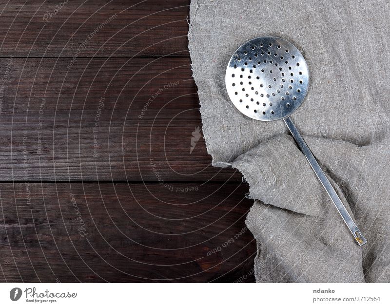 alter Eisenküchenabschäumer auf einer grauen Leinenserviette Löffel Küche Werkzeug Holz Metall Stahl weiß Sieb Gitter Silber rostfrei Gerät Handgriff Haushalt