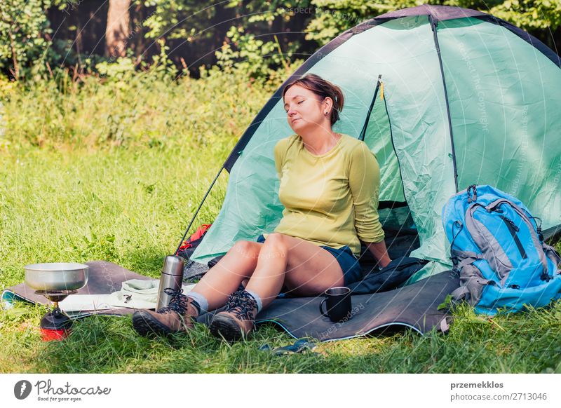 Einen Urlaub auf dem Campingplatz verbringen. Frau, die sich neben dem Zelt ausruht. Lifestyle Erholung Ferien & Urlaub & Reisen Tourismus Ausflug Abenteuer