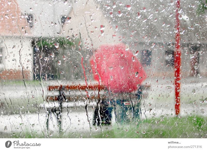 Bei Regenwetter mit Regenschirm auf der Bank chillen sitzen Mensch Wassertropfen Wetter schlechtes Wetter nass rot Fensterscheibe Glas Rinnsal Einsamkeit trist