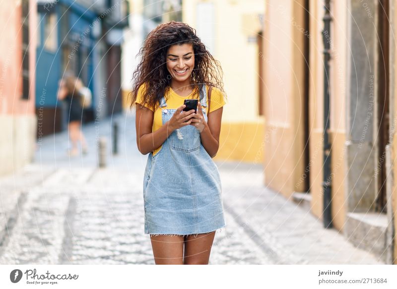 Afrikanische Frau, die auf der Straße geht und ihr Smartphone ansieht. Lifestyle Stil Glück schön Haare & Frisuren Telefon PDA Technik & Technologie Mensch