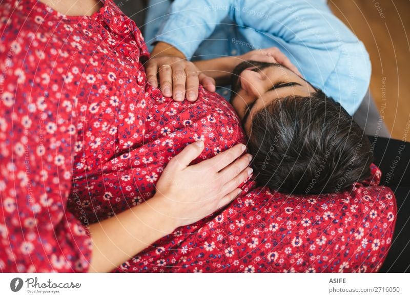 Glücklicher Mann, der zu Hause auf dem Sofa zuhört und den Bauch seiner schwangeren Frau berührt schön Körper Baby Erwachsene Eltern Mutter Vater