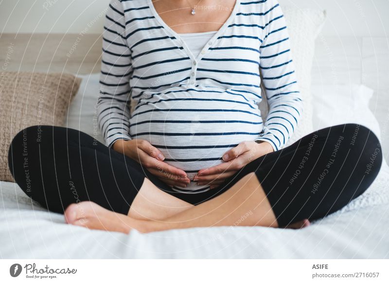 Schwangere Frau entspannt sich auf dem Bett Glück Körper Erholung Meditation Freizeit & Hobby Yoga Mensch Baby Erwachsene Eltern Mutter Hand T-Shirt berühren