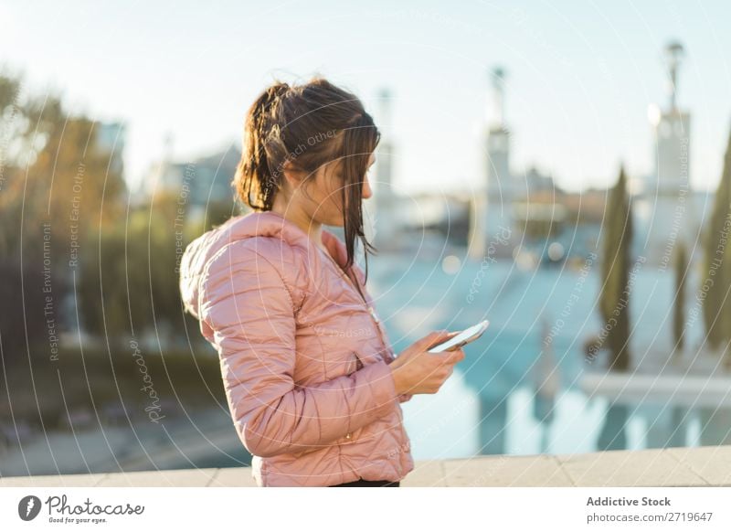 Hübsche Frau steht mit Smartphone auf der Straße. hübsch PDA Park Glück schön Telefon Jugendliche Mobile attraktiv Lifestyle Natur Außenaufnahme heiter Porträt