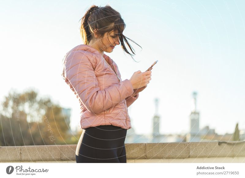 Hübsche Frau steht mit Smartphone auf der Straße. hübsch PDA Park Glück schön Telefon Jugendliche Mobile Lächeln attraktiv Lifestyle Natur Außenaufnahme heiter