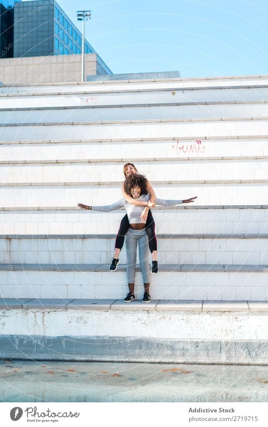 Frau, die ihren Freund hinter ihrem Rücken trägt. sportlich Zusammensein hübsch Jugendliche heiter Lächeln Freitreppe springen strecken schön Sport