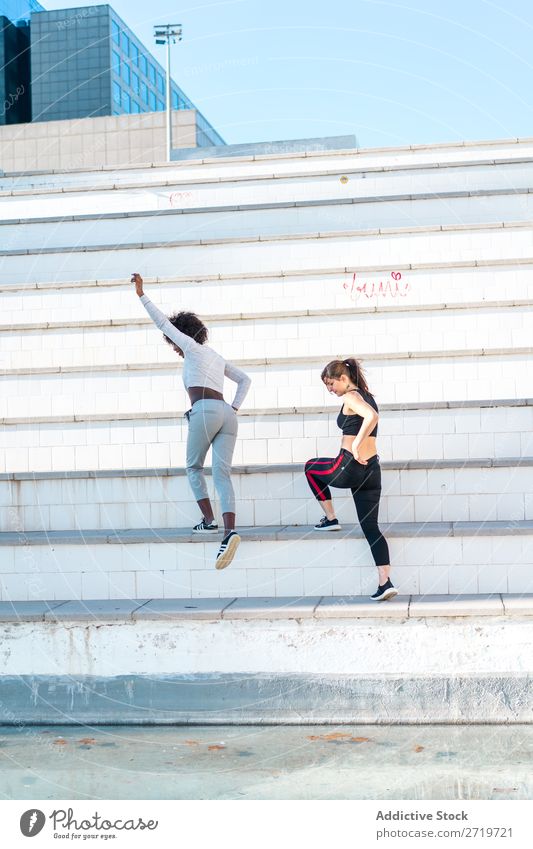 Hübsche, fitte Frauen, die zusammen springen. sportlich Zusammensein hübsch Jugendliche heiter Freitreppe strecken schön Sport multiethnisch