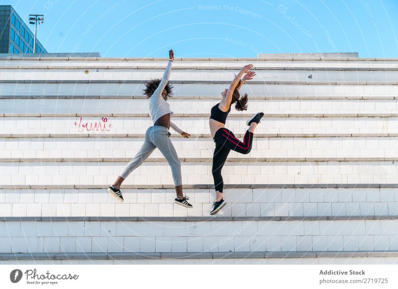 Hübsche, fitte Frauen, die zusammen springen. sportlich Zusammensein hübsch Jugendliche heiter Lächeln Freitreppe strecken schön Sport multiethnisch