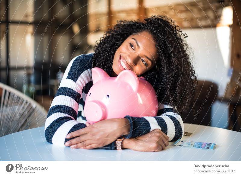 Schwarze Frau umarmt ihr Sparschwein. Spardose Einsparungen Erfolg Business Bargeld schwarz Geld Geldmünzen Euro schön Glück heiter Investition Vermögen
