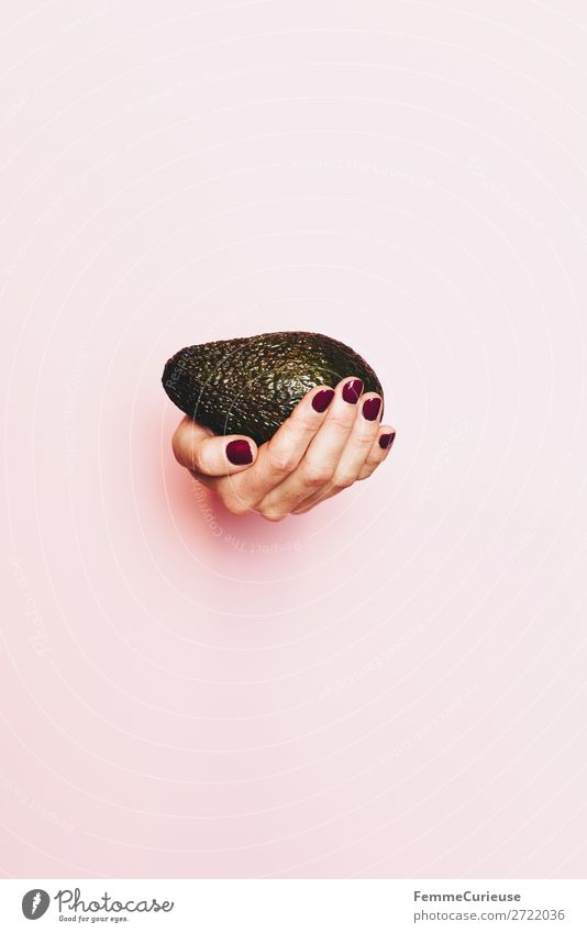 Hand of a woman holding an avocado Lebensmittel Ernährung genießen Gesunde Ernährung Vegetarische Ernährung Vegane Ernährung Avocado festhalten rosa Nagellack
