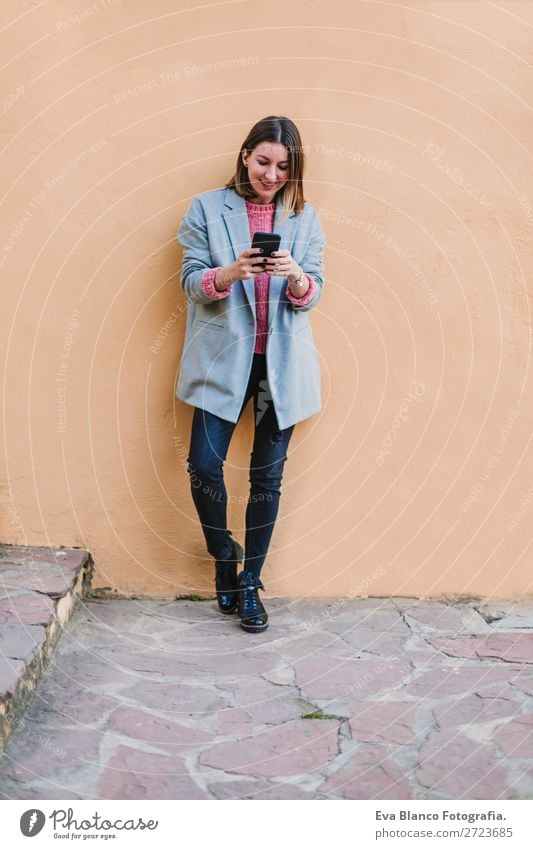 Porträt einer jungen schönen Frau im Freien Lifestyle Stil Glück Handy Technik & Technologie Internet Erwachsene Herbst Stadt Straße Mode Bekleidung