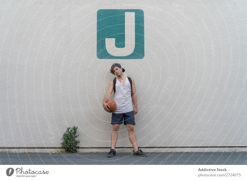 Mann mit Basketball an der Wand posierend Körperhaltung Straße Sportbekleidung stehen Lifestyle Erholung Jugendliche selbstbewußt Spielen Ball Spieler Athlet