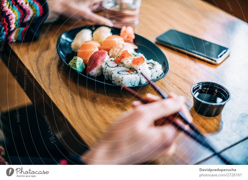 Getreidefrau beim Sushi essen Frau Hand Lebensmittel Soja maki Kalifornische Walze Essstäbchen Brötchen Feldfrüchte unkenntlich anonym Nahaufnahme Porträt Lachs