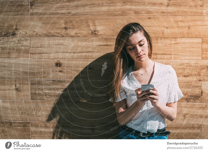 Glückliche Frau mit Smartphone an einer Holzwand PDA Telefon Mobile Mitteilung Gerät Lächeln Wegsehen Porträt Hintergrundbild Sommer Wand Halt klug Jugendliche