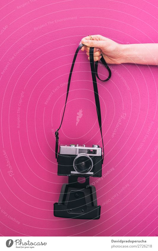 Hand haltend eine Vintage-Kamera isoliert an der rosa Wand Arme Fotokamera altehrwürdig retro vereinzelt Studioaufnahme Halt Freizeit & Hobby