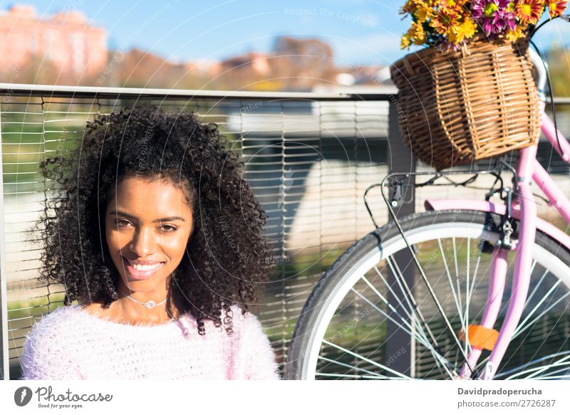 Schwarze junge Frau sitzt mit ihrem alten Fahrrad am Fluss. Mädchen schön retro Blume Glück altehrwürdig Blumenstrauß rosa Sommer Jugendliche hübsch Frühling