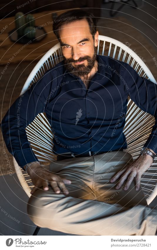 Porträt eines reifen Mannes, der auf dem Stuhl sitzt und nachdenklich posiert. alt Sitz Vollbart unrasiert Entwurf Brunnen angekleidet Herr Kaukasier Lächeln