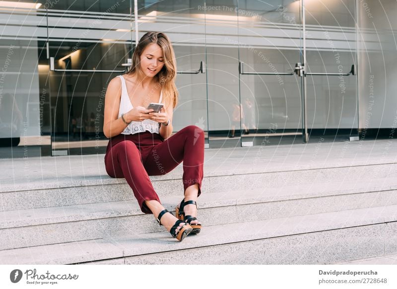 Schöne junge Frau sitzt in der Treppe auf dem Handy. blond Telefon Mobile Technik & Technologie sitzen Außenaufnahme Jugendliche Freitreppe Beautyfotografie