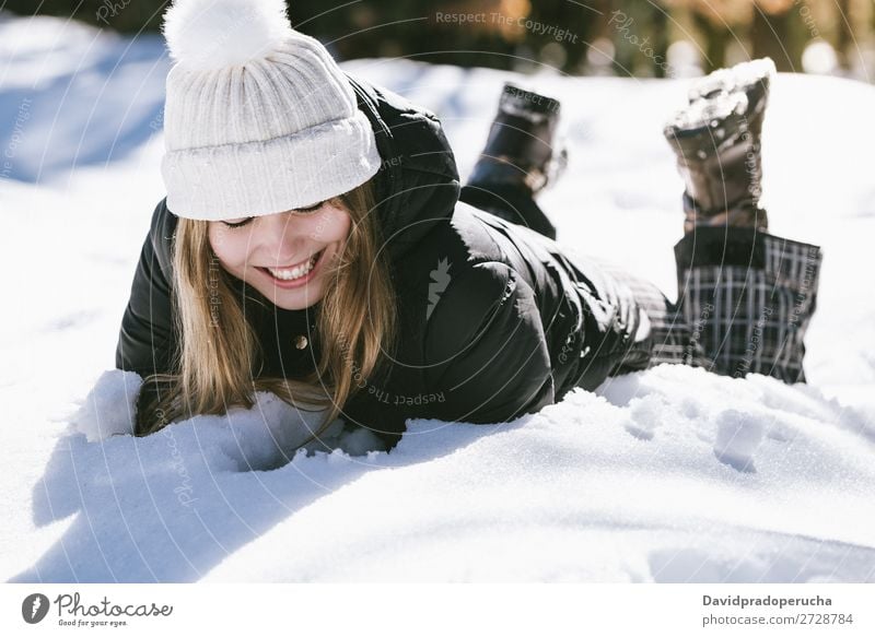 Junge süße Frau liegend spielend und schneesicher im Winter Schnee Porträt Jugendliche Glück Spielen lügen blond schön Mädchen Kaukasier Erwachsene Mode Haut