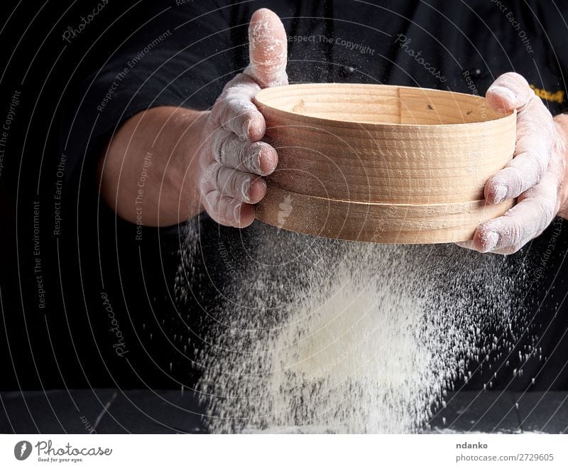 Mann siebt weißes Weizenmehl Teigwaren Backwaren Brot Ernährung Tisch Küche Koch Mensch Erwachsene Hand Sieb Holz Bewegung machen frisch schwarz backen Bäcker