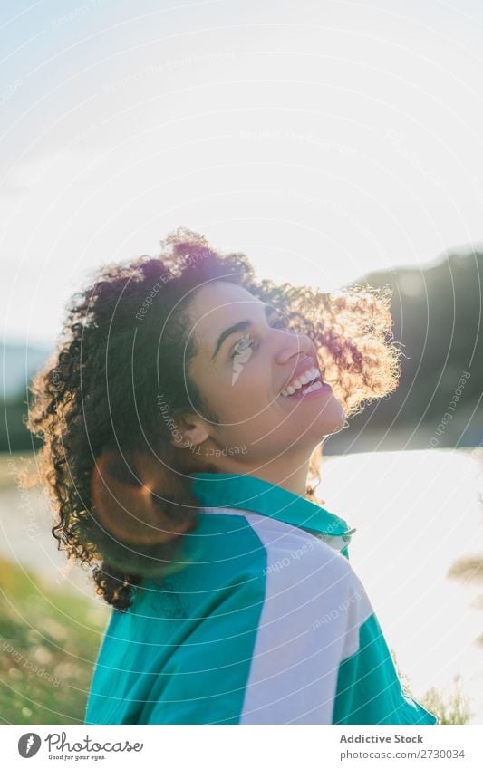 Lockenförmige Frau, die im Sonnenlicht auf der Natur posiert. Sommer genießen Körperhaltung Menschliches Gesicht Landschaft Farbe Porträt lockig ruhig