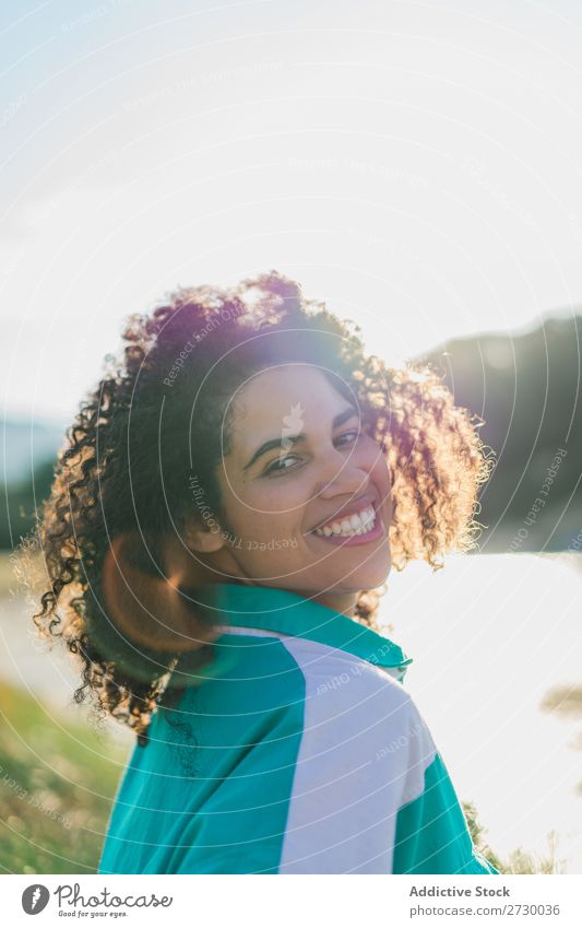 Lockenförmige Frau, die im Sonnenlicht auf der Natur posiert. Sommer genießen Körperhaltung Menschliches Gesicht Landschaft Farbe Porträt lockig ruhig