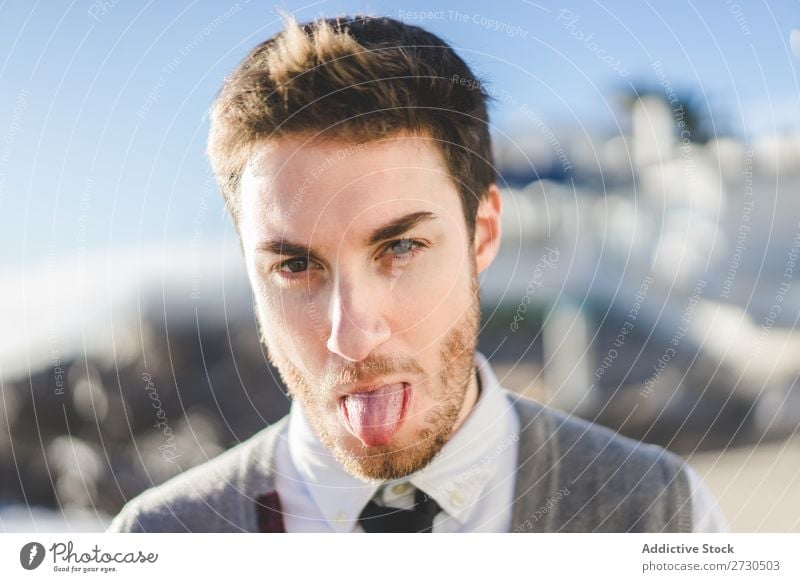 Mann zeigt Zunge im Sonnenlicht ausspannen spielerisch Menschliches Gesicht Porträt Grimasse Fröhlichkeit Zunge zeigen Aufregung Spielen Ausdruck konfrontierend