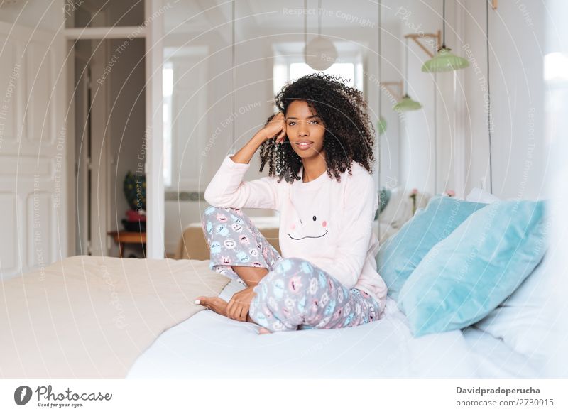 Glückliche, schöne, junge, schwarze Frau, die entspannt im Bett sitzt. Lächeln Erholung wach niedlich gemütlich Schlafanzug Pyjama Winter kalt sitzen Reflexion