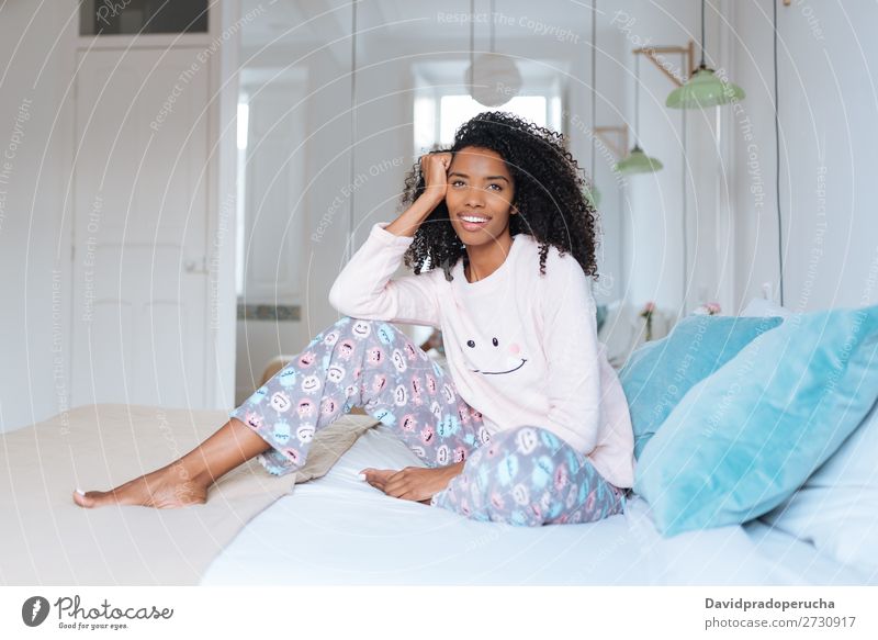 Glückliche, schöne, junge, schwarze Frau, die entspannt im Bett sitzt. Lächeln Erholung wach niedlich gemütlich Schlafanzug Pyjama Winter kalt sitzen Reflexion
