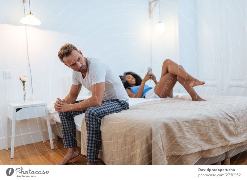 Junges schönes interrassisches Paar im Bett, das mit Untreue-Problemen gestresst ist. Erwachsene Wut Person gemischter Abstammung Rennsport Jugendliche