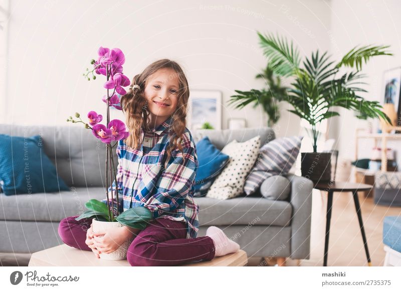 glückliches Kind posiert mit Orchideenblume Topf Lifestyle exotisch schön Wohnung Wohnzimmer Gartenarbeit Pflanze Blume Blatt Wachstum klein modern neu rosa