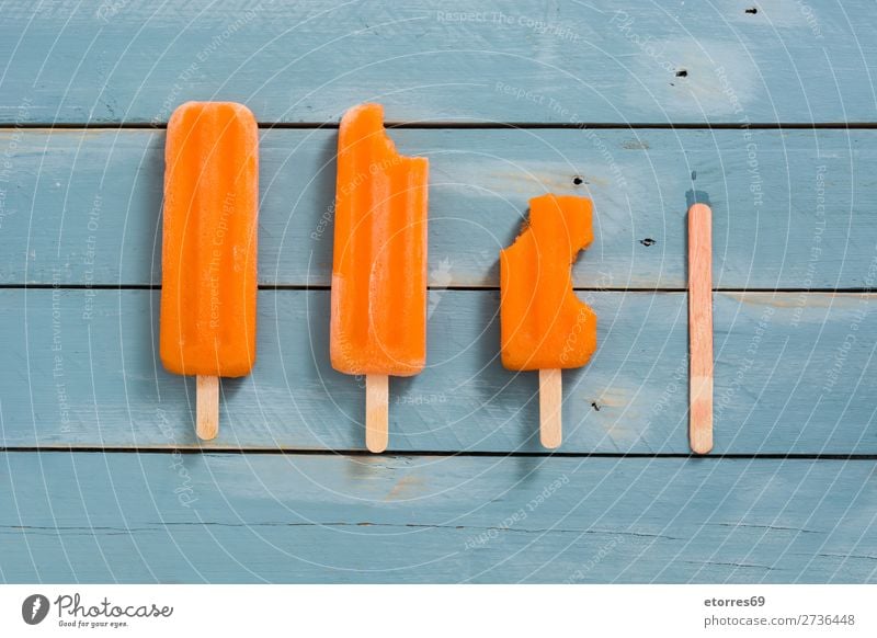 Orange Stieleis am blauen Holz Kuchen orange Sommer Eis Speiseeis kalt Lebensmittel Gesunde Ernährung Foodfotografie Dessert gefroren Zuckerguß Vegane Ernährung