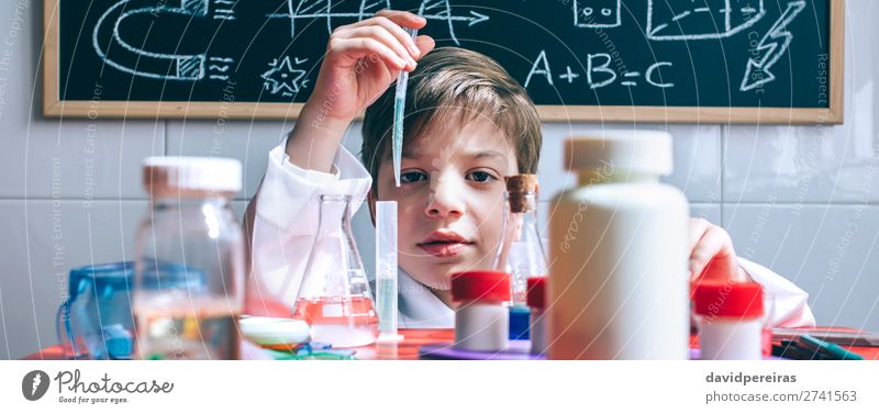 Kind spielt mit chemischen Flüssigkeiten über dem Tisch. Flasche Glück Spielen Wissenschaften Klassenraum Tafel Labor Internet Mensch Junge Kindheit Hand