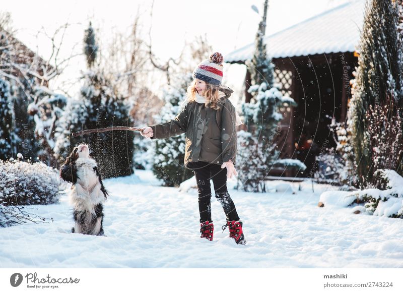 glückliches Kind beim Spielen mit dem Hund im Winter Freude Glück stricken Ferien & Urlaub & Reisen Schnee Garten Tier Wetter Wald Schal Hut Haustier Tropfen