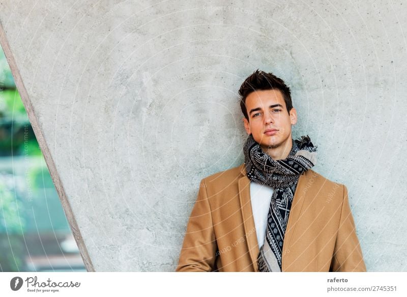 Junger Mann mit Mantel und Schal, der sich an eine Wand lehnt. Lifestyle elegant Stil schön Haare & Frisuren Mensch maskulin Jugendliche Erwachsene 1