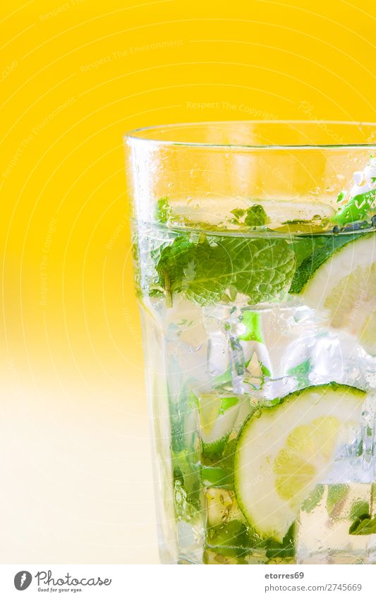 Mojito-Cocktail im Glas auf gelbem Hintergrund. Getränk trinken Alkohol Erfrischung Sommer Kalk grün Minze Saft Rum kalt Eis Mixer Frucht Zutaten Zucker