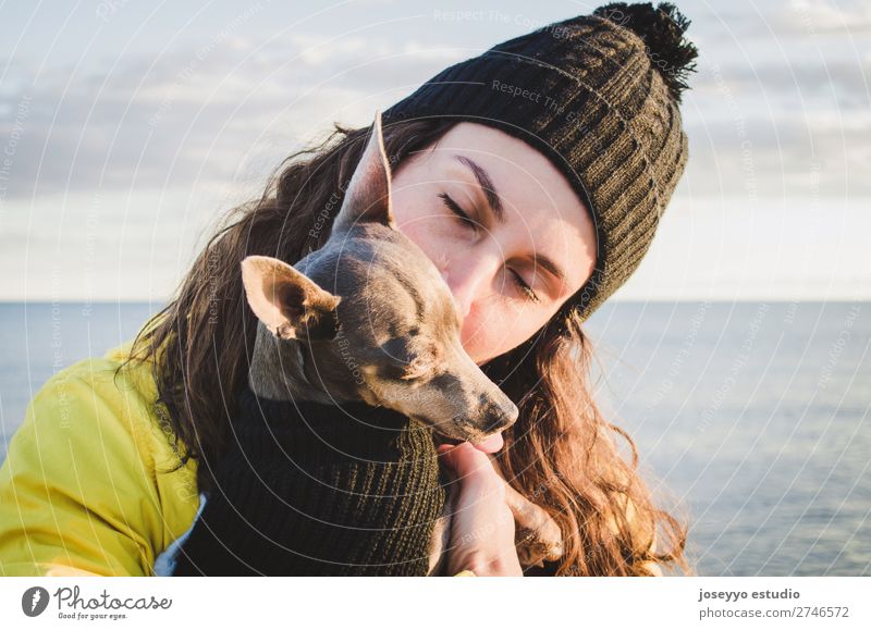 Frau mit ihrem kleinen Hund am Strand Lifestyle Erholung Ausflug Freiheit Winter Freundschaft 30-45 Jahre Erwachsene Natur Tier Horizont Küste Jacke Mantel Hut
