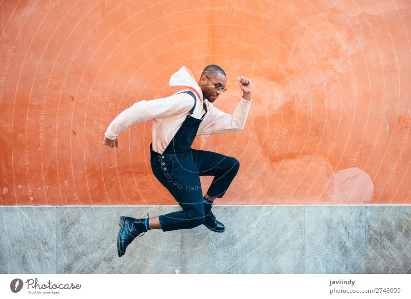 Junger schwarzer Mann in Freizeitkleidung springt im städtischen Hintergrund Lifestyle Freude Glück schön Mensch maskulin Junger Mann Jugendliche Erwachsene 1