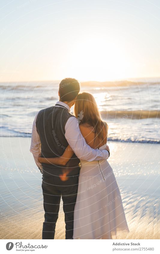 Umarmung des Hochzeitspaares bei Sonnenuntergang Paar Strand Sonnenlicht Genuss stehen umarmend Fröhlichkeit Liebe Beautyfotografie Zusammensein romantisch