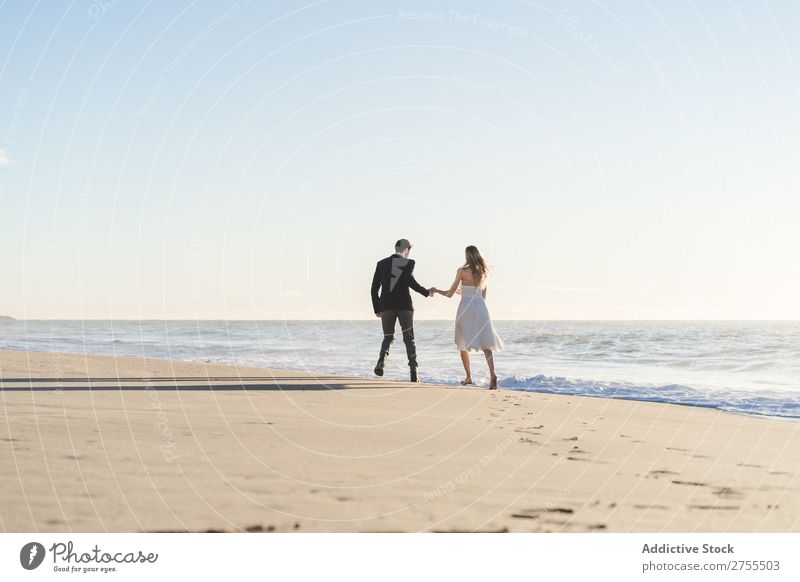 Romantische Braut und Bräutigam beim Spaziergang am Strand Paar striegeln verliebt romantisch Partnerschaft Händchenhalten träumen Jugendliche Meer Engagement