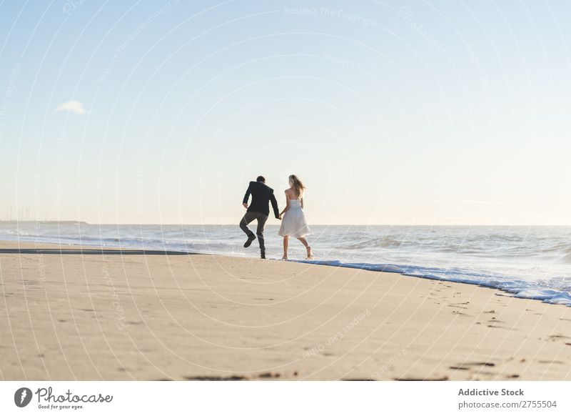 Romantische Braut und Bräutigam beim Spaziergang am Strand Paar striegeln verliebt romantisch Partnerschaft Händchenhalten träumen Jugendliche Meer Engagement